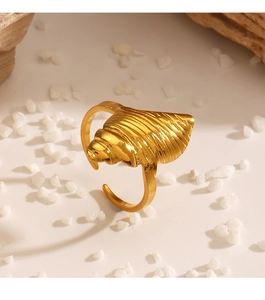 Detailed view of gold shell ring with textured ridges on white beach pebbles