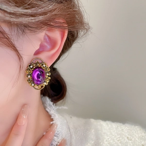 Detail of vintage French style gold ear clip with purple oval gem and white stone accents