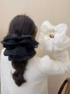 Detailed macro view of large pleated mesh scrunchies in classic black and white colors