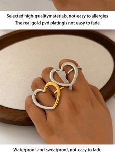 Detail of PVD gold plated hollow heart rings on wooden tray with model hands