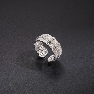 Detail of silver lace cutout ring with white zircon stones on black background