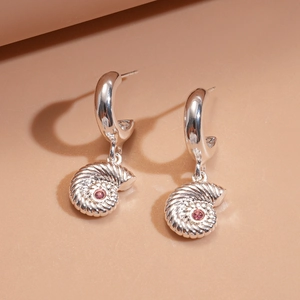 Macro shot of silver shell drop earrings with pink gems on a minimalist background