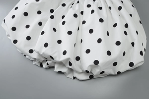 Detailed view of white fabric with black polka dots featuring elegant natural pleats