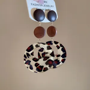 Detail view of geometric drop earrings featuring leopard print rings and silver pins