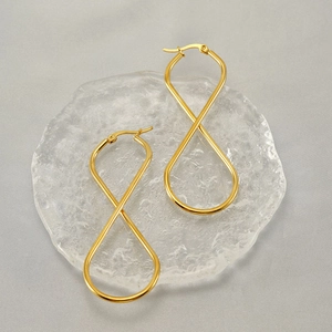 Macro detail of golden twist infinity earrings on a textured decorative glass plate