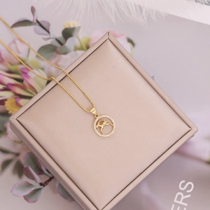 Macro shot of 18K gold zodiac pendant with white zircons on a champagne jewelry box