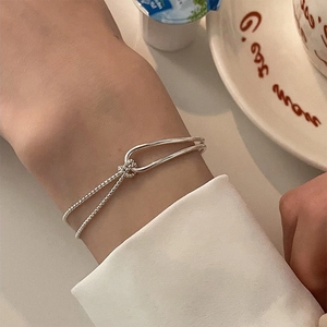 Minimalist silver dual-strand chain bracelet with U-shaped buckle and knot detail in lifestyle setting