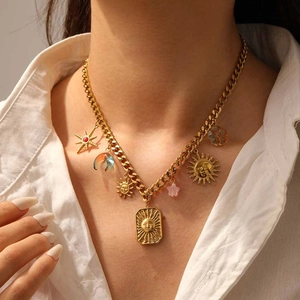 Detail view of gold necklace with sun, moon, and floral charms on a female model