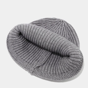 Gros plan détaillé montrant la texture en maille côtelée de ce bonnet d'hiver gris chaud