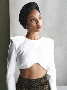 Details des weißen langärmeligen Crop-Tops mit Schulterpolstern und Glitzersäumen und Perlen