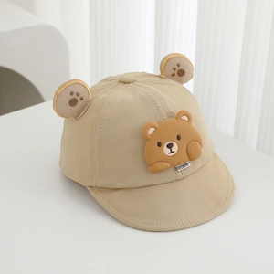 Detailed close-up of beige baby cap with 3D cartoon bear ears and soft silicone patch