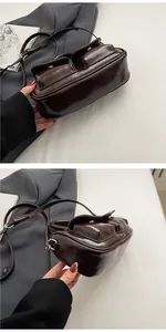 Detail view of coffee brown patent leather saddle bag with double front pockets and silver hardware