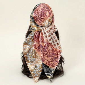 Carré en satin rose avec motif paisley et fleurs noué sur un mannequin de tête
