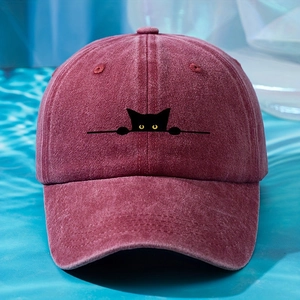 Close-up of burgundy washed cotton baseball cap with black cat embroidery on light blue fabric