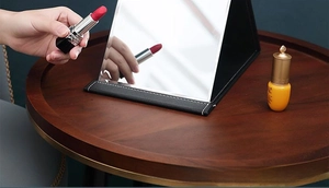 Detail of portable folding makeup mirror with black PU leather cover and white stitching