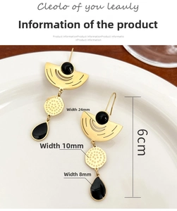 Detailed view of long gold crystal earrings with size labels on a white ceramic plate