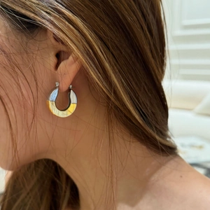 Detailed view of bicolor 18k gold plated C hoop earrings worn on model's ear