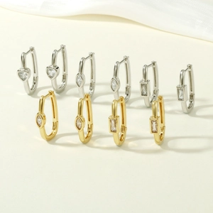 Detailed macro view of heart and geometric zircon earrings in gold and silver finishes