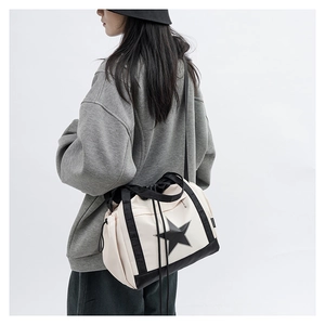 Detail view of beige star print crossbody bag with drawstring closure and black strap