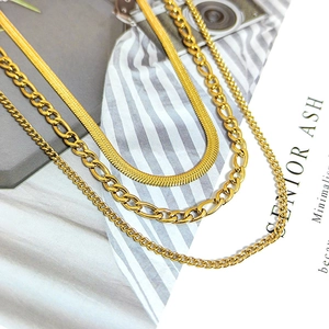 Golden titanium steel jewelry set featuring layered Figaro, herringbone, and curb chains