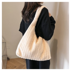 Detail view of large plush tote bag in beige faux fur shown on model shoulder