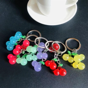 Colorful resin cherry keychains in translucent jelly colors on a dark background