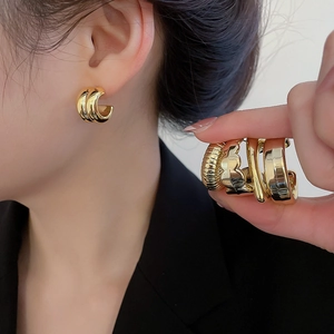 Close-up of gold chunky hoop earrings set showing polished and textured metal finishes