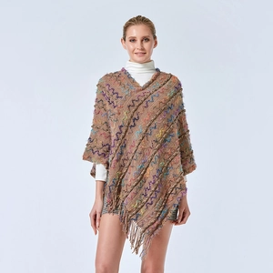 Détail du poncho en tricot camel avec des textures ondulées colorées et des franges