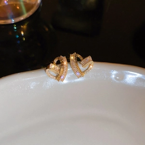 Macro detail of gold plated heart stud earrings featuring sparkling cubic zirconia stones