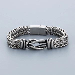 Gros plan du bracelet gourmette argenté vintage avec noeud central et maillons tressés