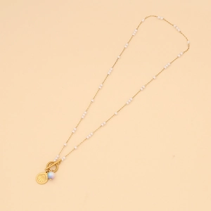 Detail of gold chain necklace featuring white beads and scallop shell pendant