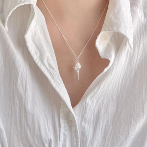 Close-up of a 925 silver conch pendant necklace worn by a model in a white shirt