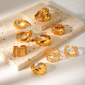 Collection of geometric 18K gold plated stainless steel rings on a stone tray