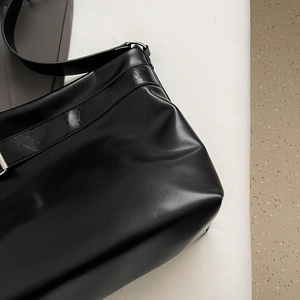 Gros plan détaillé de la texture du cuir PU noir et des ferrures de ce sac fourre-tout