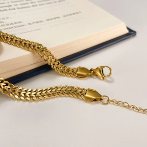 Detailed close-up of golden double-strand woven bracelet with lobster clasp and extender