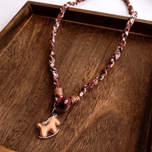 Detail of red floral fabric braided necklace with wooden rocking horse pendant