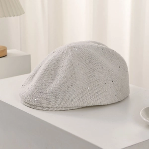 Detail of light gray knitted beret with subtle silver sequins on white display stand