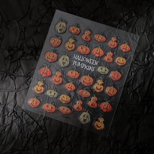 Close-up of Halloween pumpkin nail decals with orange and grey patterns on dark background