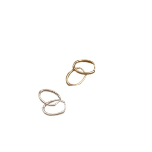 Orecchini a cerchio ovali minimalisti in oro 18 carati e argento su sfondo bianco