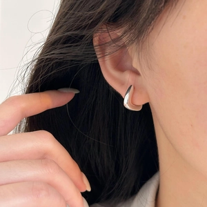 Detail view of wide C-shaped silver hoop earrings with high-polish mirror finish on model