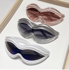 Detail showing Y2K lip-shaped sunglasses in pink, grey, and white with wavy frames