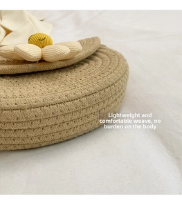 Detail of handwoven round crossbody bag with a smiling yellow floral decorative element