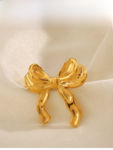 Detail of 18K gold plated bow ring showing polished mirror finish on silk fabric