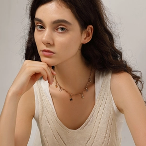 Detail view of model wearing gold stainless steel necklace with star and heart charms