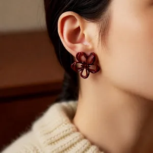 Elegant deep red hollow flower earrings on model featuring minimalist five-petal design
