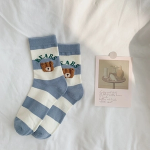 Detail of blue and white striped cotton socks with brown bear embroidery and ribbed texture