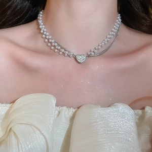 Detail of elegant double-layer pearl necklace featuring a diamond-studded heart pendant