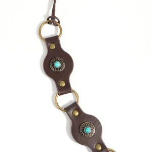 Detail of vintage brown leather belt featuring turquoise inlays and brass metal rings