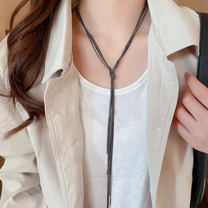 Detail of multi-layer knotted black metal chain tassel necklace on model outfit