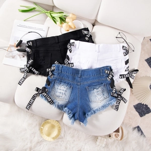 Dettaglio degli shorts Y2K in denim con nastri LOVE stringati e orli grezzi sfilacciati